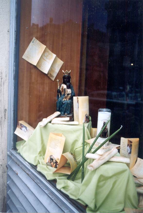 Window display in Marseilles showing Notre Dame de la Confession, green candles, and boat-shaped cookies called navettes